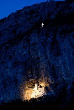 a cross is lit up on the side of a mountain with a light in it