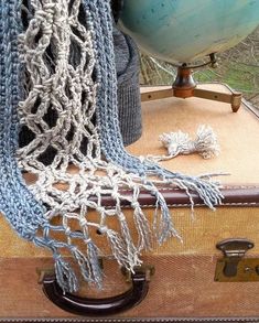 a piece of luggage sitting on top of a wooden floor next to a blue and white scarf