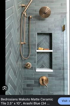 a bathroom shower with gray tile and gold faucet, next to a white shelf