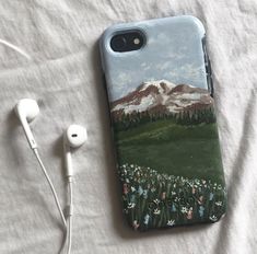 an iphone case is sitting on a bed with headphones and earbuds next to it