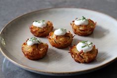 small appetizers on a white plate with green garnishes and sour cream