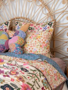 a bed with colorful pillows on it and a wicker headboard behind the bed