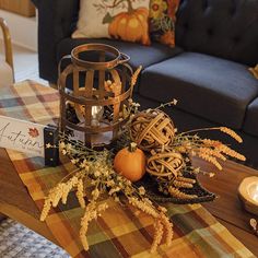 a table topped with a candle and some pumpkins on top of it next to a couch