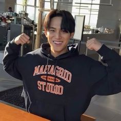 a young man wearing a black hoodie posing for the camera with his fist up