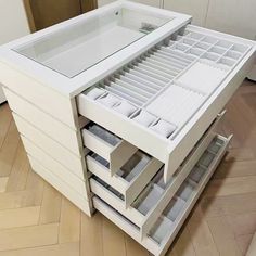 a white cabinet with drawers on top of it in the middle of a wooden floor