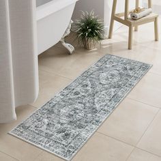 a bath tub sitting next to a rug on top of a tiled floor in a bathroom