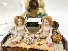 two little figurines sitting on top of a wooden table next to a glass dome