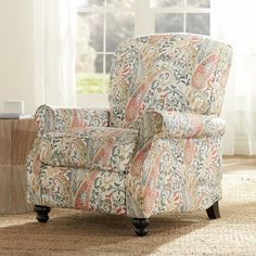 a living room area with a chair and rug on the floor, windows in the background