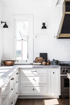 a kitchen with white cabinets and an oven in the center, along with wooden flooring