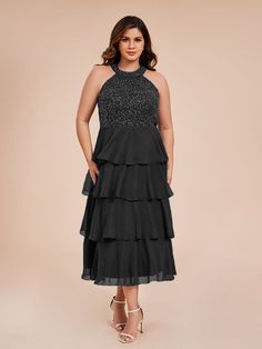 a woman wearing a black dress with tiered layers and sequins on the top