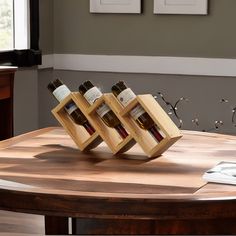 three bottles of wine are in wooden holders on a table with a laptop and mouse