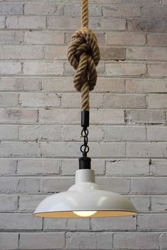 a white light hanging from a brick wall with a rope attached to the lamp shade