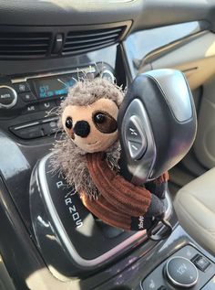 a stuffed animal is sitting in the center console of a car while wearing a scarf