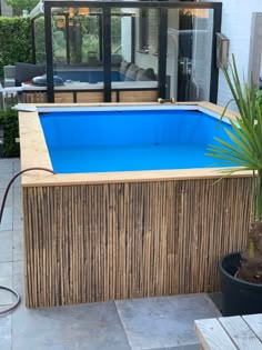 a small pool in the middle of a patio with a wooden fence and potted plant