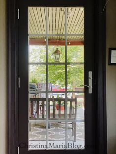 the front door to a house with a table and chairs behind glass doors that lead out onto a patio