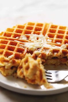 a white plate topped with waffles covered in butter and syrup next to a fork