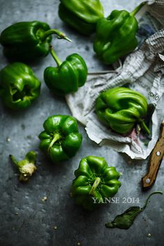 some green peppers are on a table next to a pair of scissors