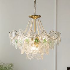 a chandelier hanging from the ceiling in a room with white walls and green plants