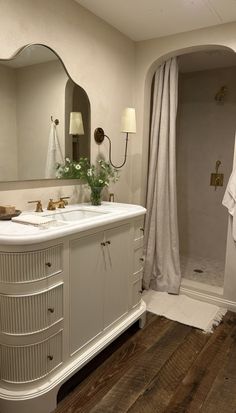 a white bathroom with two sinks and a large mirror on the wall next to a walk in shower