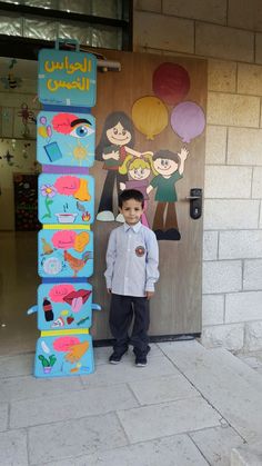 a young boy standing in front of a door decorated with children's drawings on it