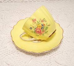 a yellow tea cup and saucer on a white tablecloth