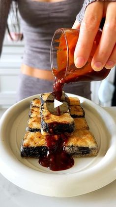 a person pouring syrup onto some food on a plate