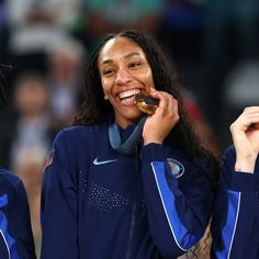 two women who are eating some kind of doughnut in front of their mouths and smiling at the camera