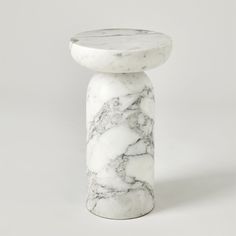 a white and black marble pedestal on a grey background