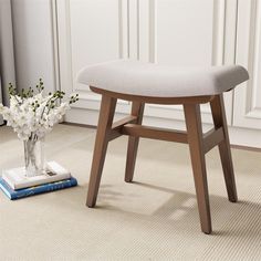 a white chair sitting on top of a rug next to a vase filled with flowers