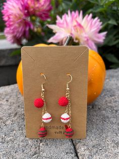 a pair of red and white earrings sitting on top of a card