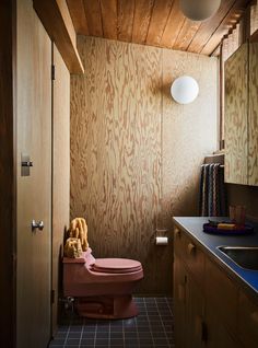 a bathroom with a toilet, sink and wooden walls