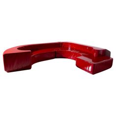 a red curved couch sitting on top of a white floor