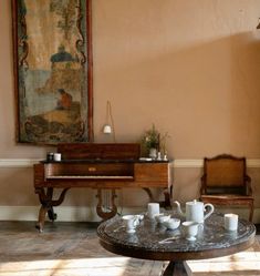 a living room filled with furniture and a table topped with cups next to a piano