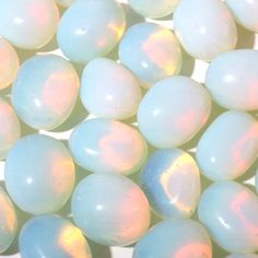 some white and blue colored eggs on a table top with the light reflecting off of them