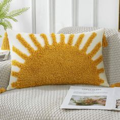 a yellow and white pillow sitting on top of a couch next to a green plant