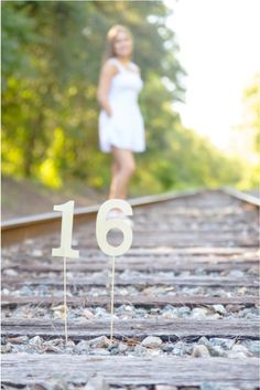 a woman standing on train tracks with the number sixteen in front of her and an arrow shaped cake topper