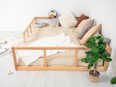 a bed with pillows and blankets on top of it next to a potted plant