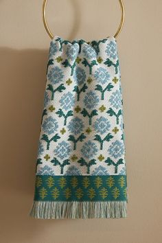 a towel hanging on a wall with a gold circular handle and blue flower pattern design