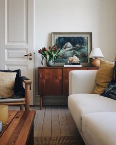 a living room filled with furniture and flowers on top of a wooden table next to a white door