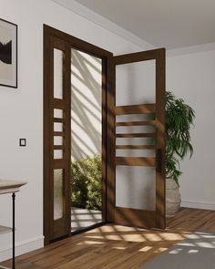 an open door in a white room with wooden floors and potted plant next to it