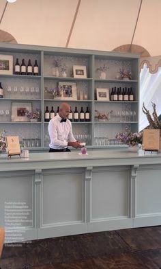 a man standing behind a bar with bottles on it