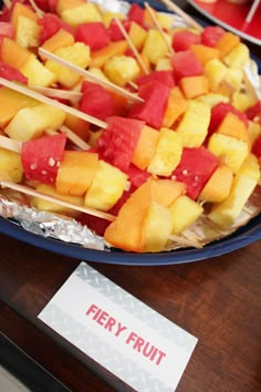 fruit skewers sitting on top of a blue plate covered in tin foil next to apples and watermelon