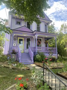 a purple house with flowers in the front yard