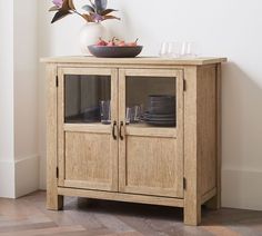 a wooden cabinet with glass doors and plates on top