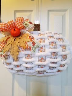 a white pumpkin shaped door hanger with fall decorations on it's front porch