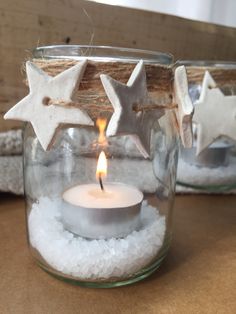 two mason jars filled with snow and lit candles