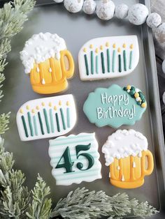 decorated cookies in the shape of beer mugs with candles and numbers are on a tray