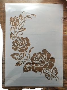 the stencil is being used to create a floral design on a piece of wood