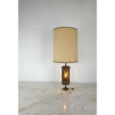 a lamp that is sitting on top of a marble table with a white wall in the background