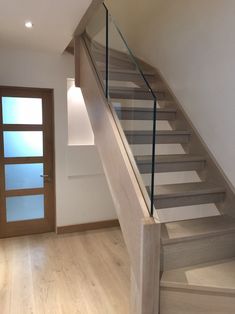 a stair case with glass railing and wood handrail